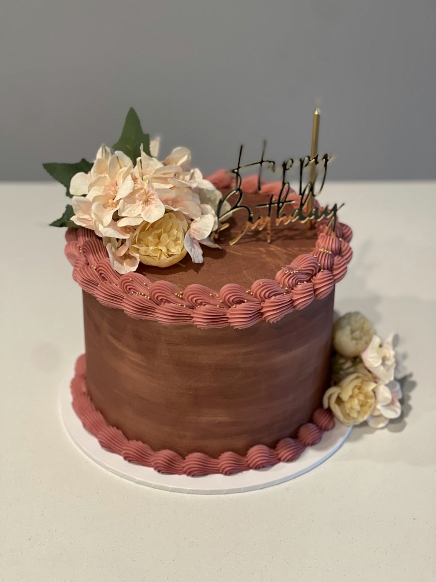 Chocolate cake with dusty-pink piping and cream roses