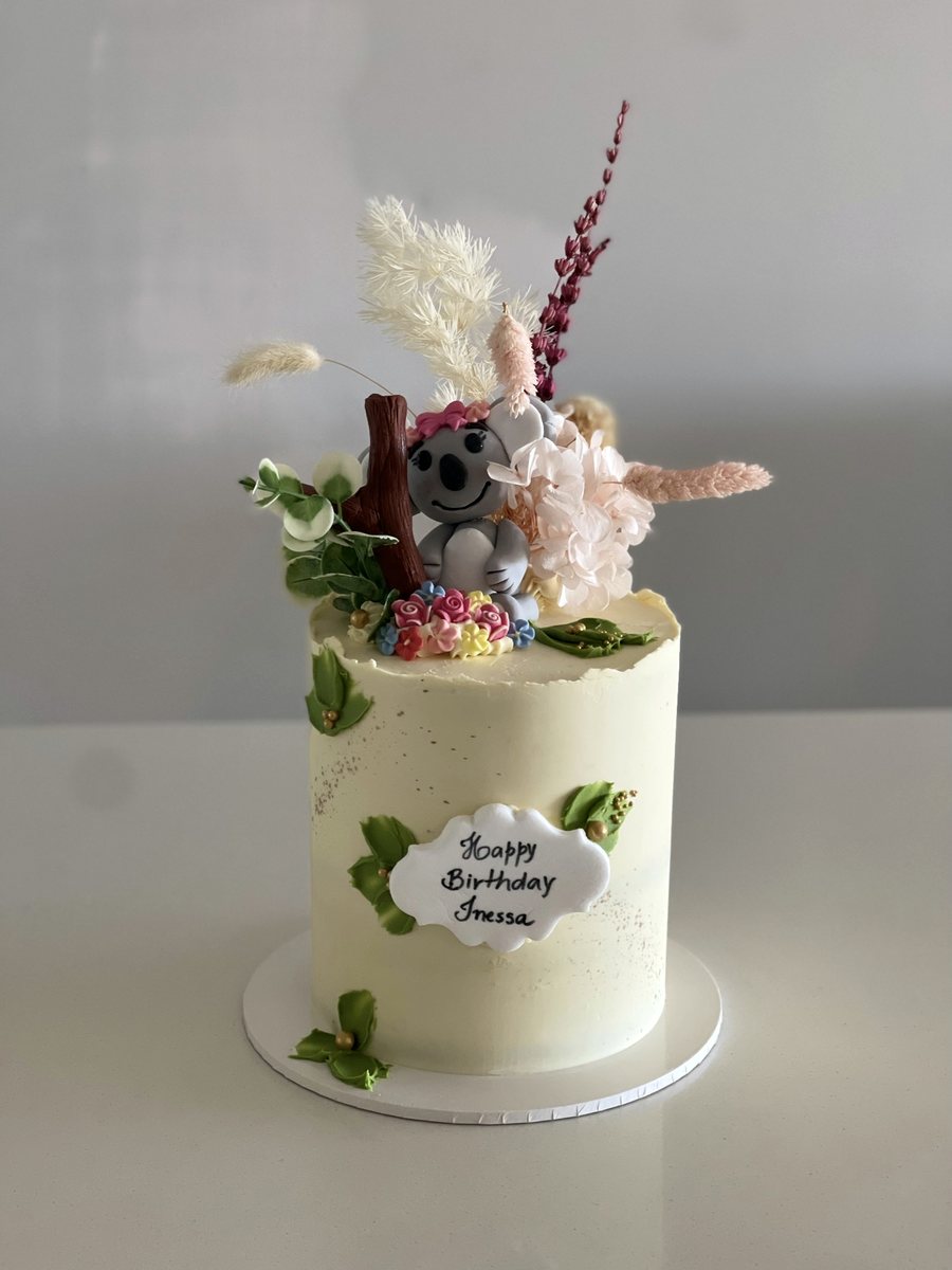 Tall cake with dried flowers and a modelled koala