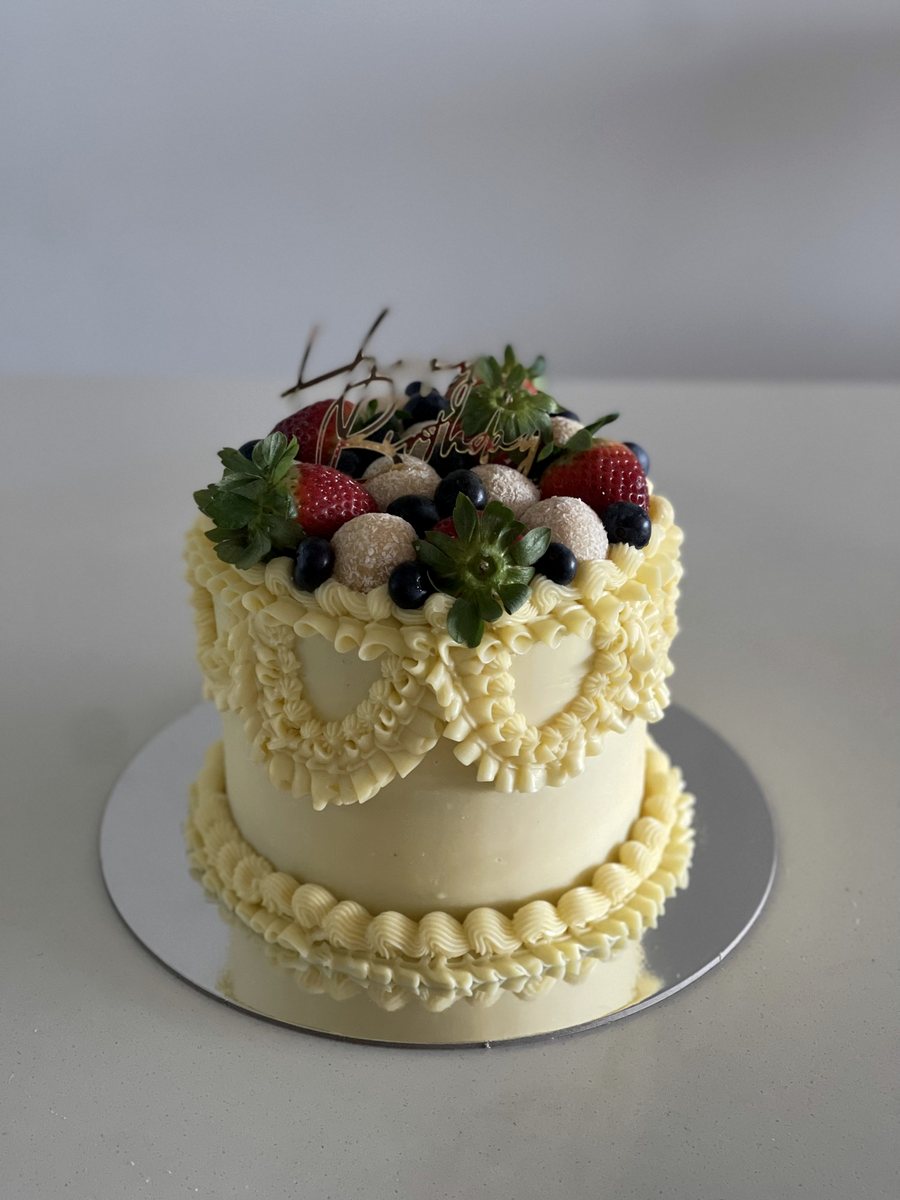 Vintage piped cake topped with berries and herbs