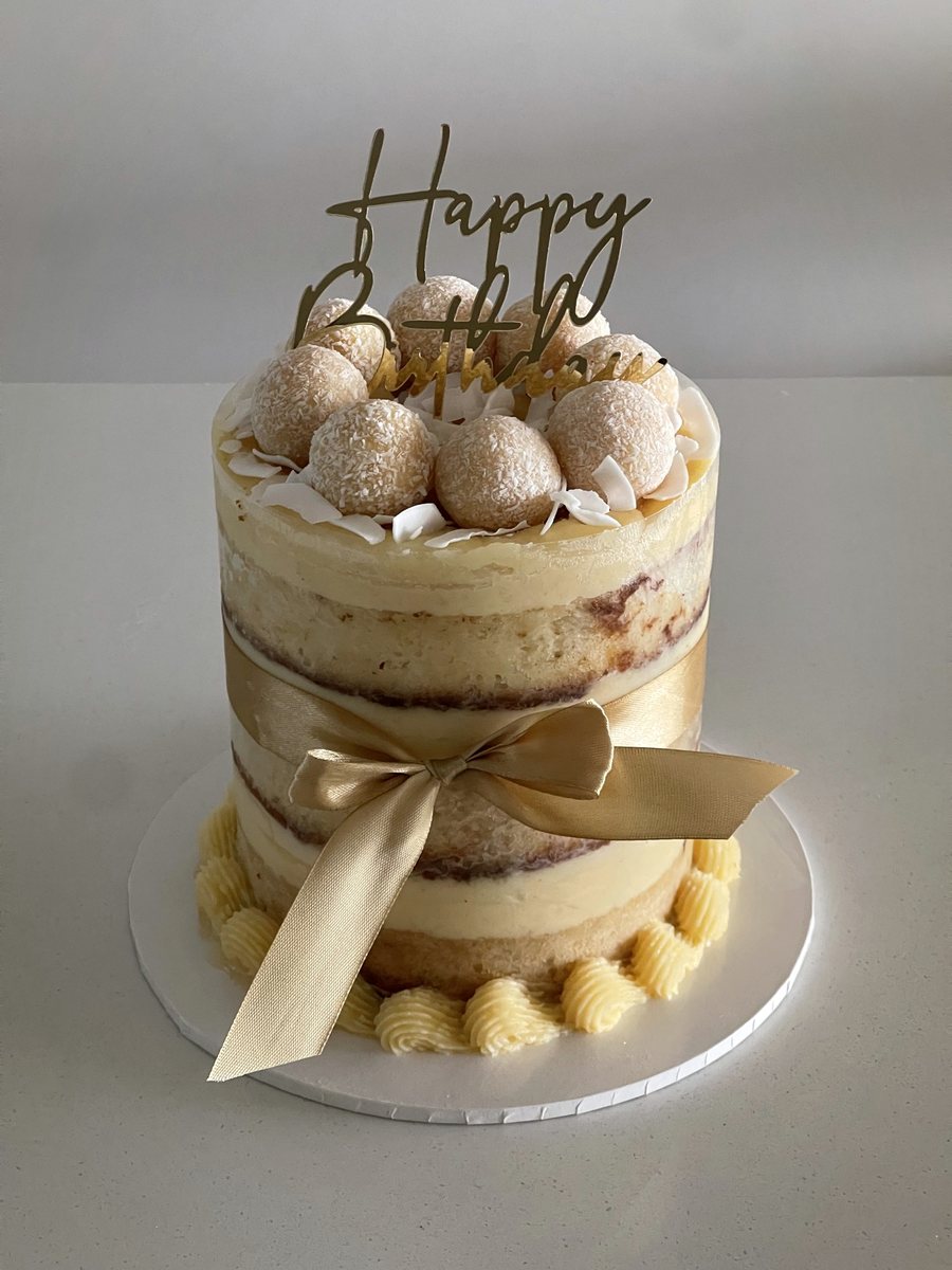 Naked cake tied with a gold ribbon and topped with golden truffles